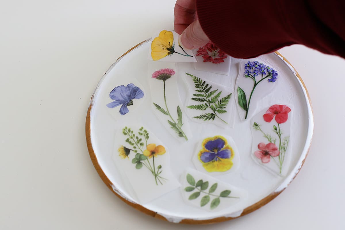 Placing rub-on transfers on a wooden plate to make sure the design is correct before applying them permanently.
