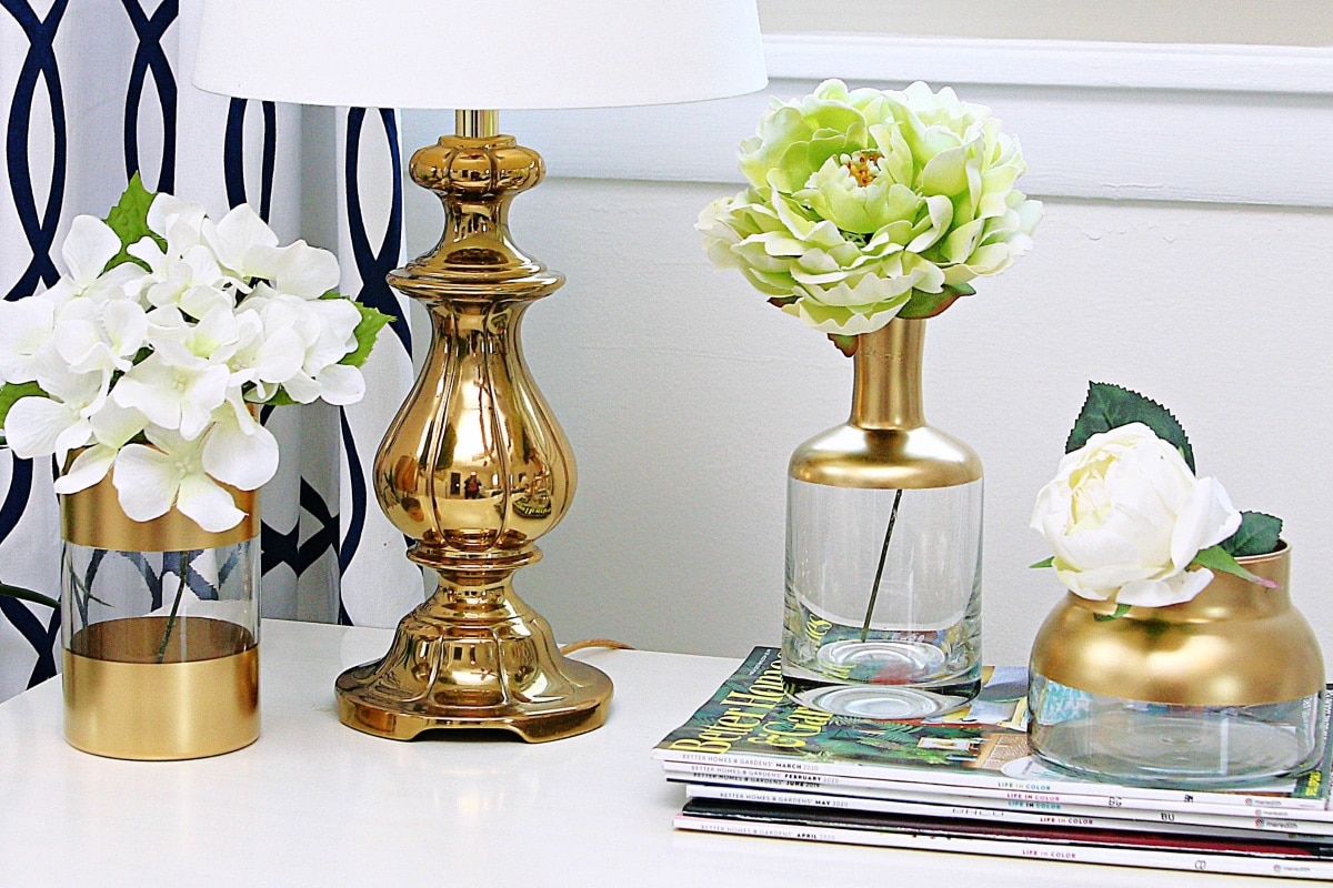 Three vases with gold accents setting on an end table.