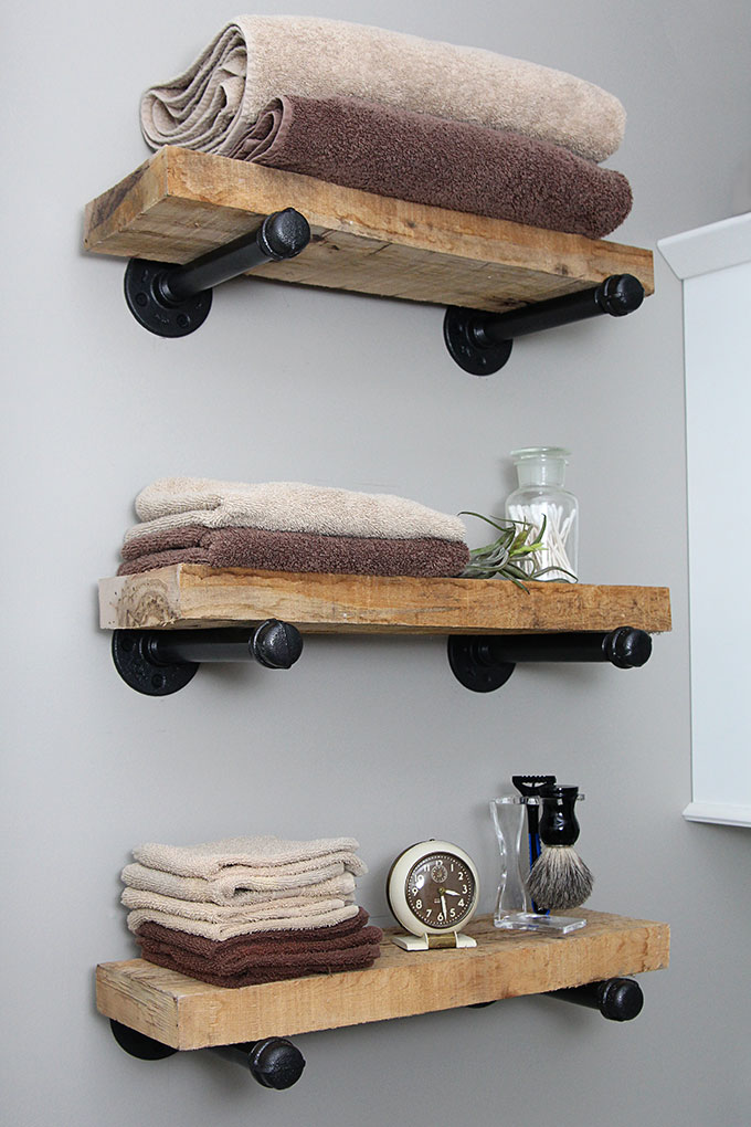 Super easy step by step tutorial for how to make DIY industrial pipe shelves at a fraction of the cost of the store bought version. These would look great with both farmhouse and industrial home decor! 3 pipe shelves topped with thick wood in a bathroom