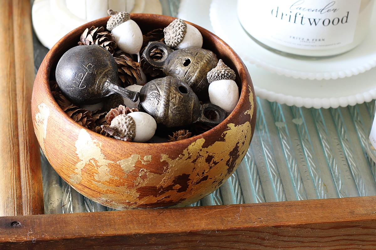 Bowl full of fall bowl filler including warm brass bells, white acorns and little pinecones.