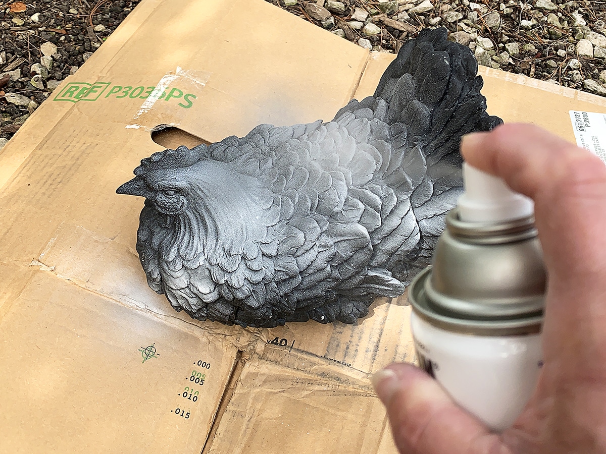 Spraying a coat of gray paint on the resin chicken.