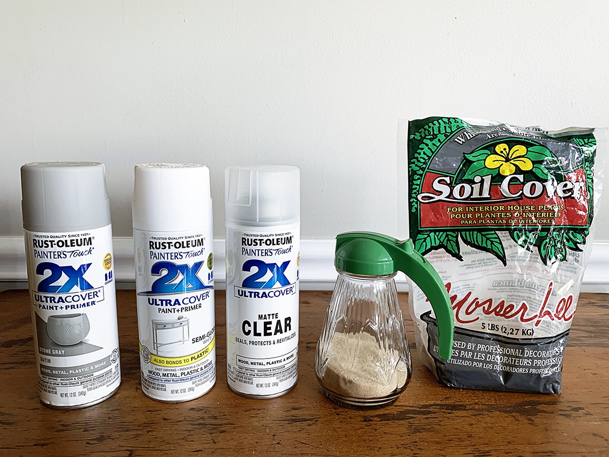 Three cans of spray paint - Stone Gray, White and Matte Clear Sealer along with a small bag of sand. 