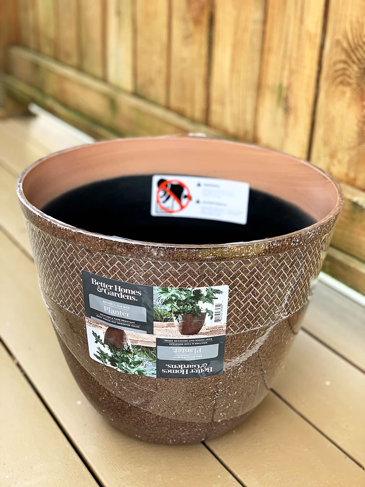 Large briwnbb flower pot being used to create a stylish garden hose holder.
