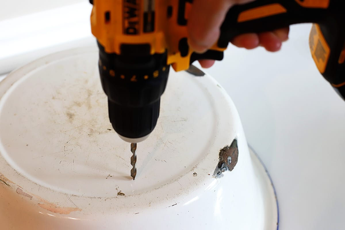 Drilling holes into the bottom of the enamelware pan to be used as a planter.