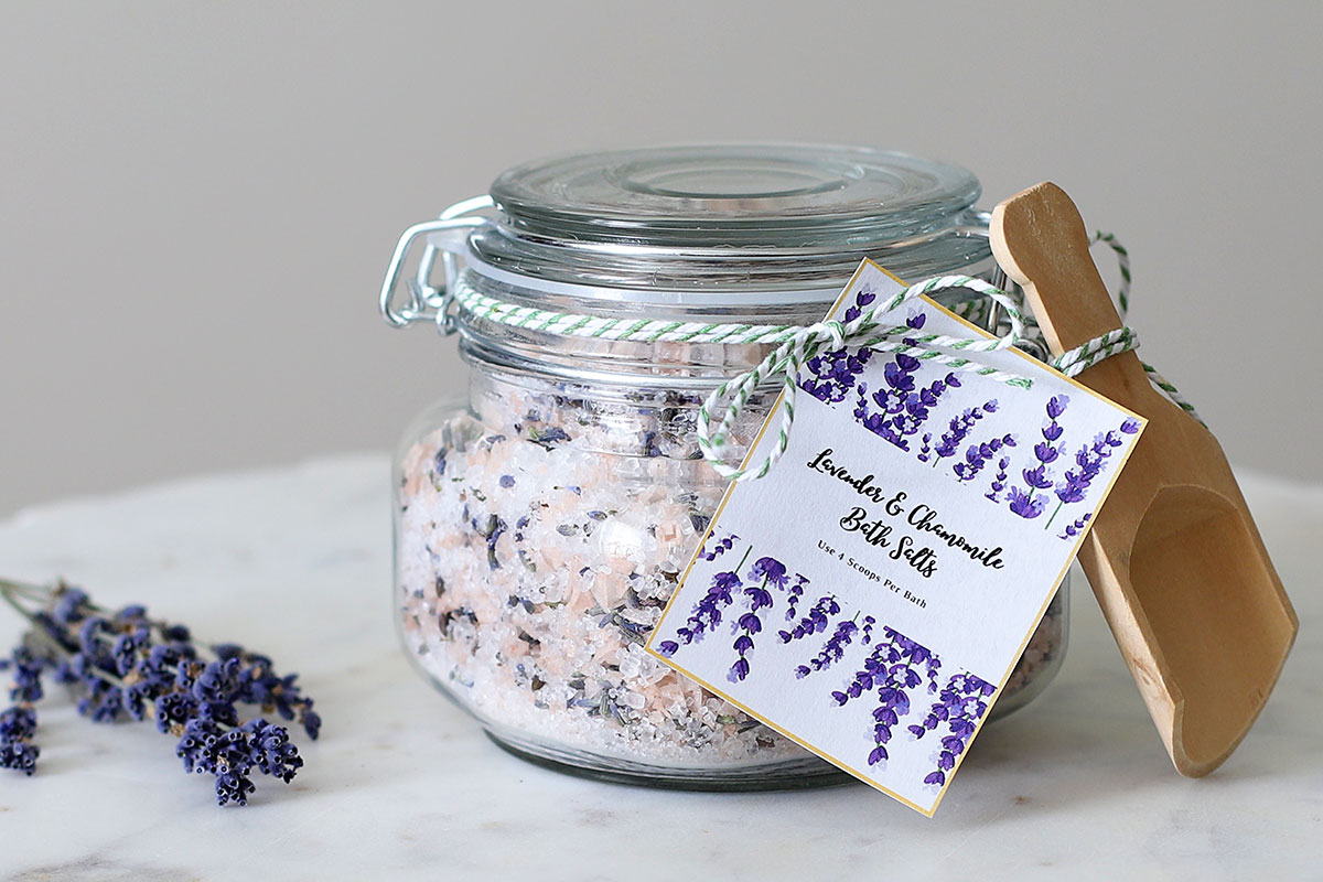 DIY lavender and chamomile bath salts in a glass jar with a wooden scoop.