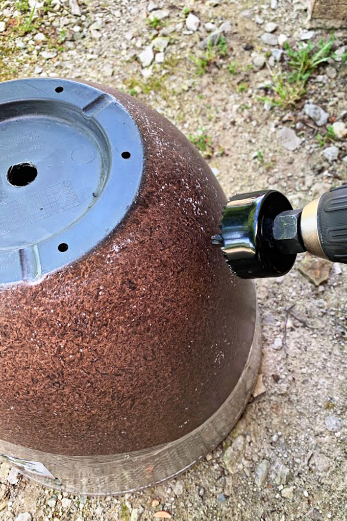 Drilling hole in the side of the flower pot to turn it into a garden hose hideaway.