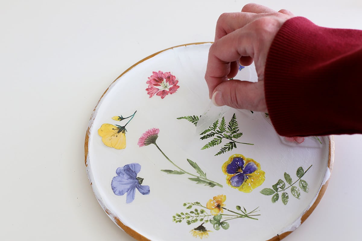 Checking to make sure the rub-on transfers have successfully transferred to the wooden platter.