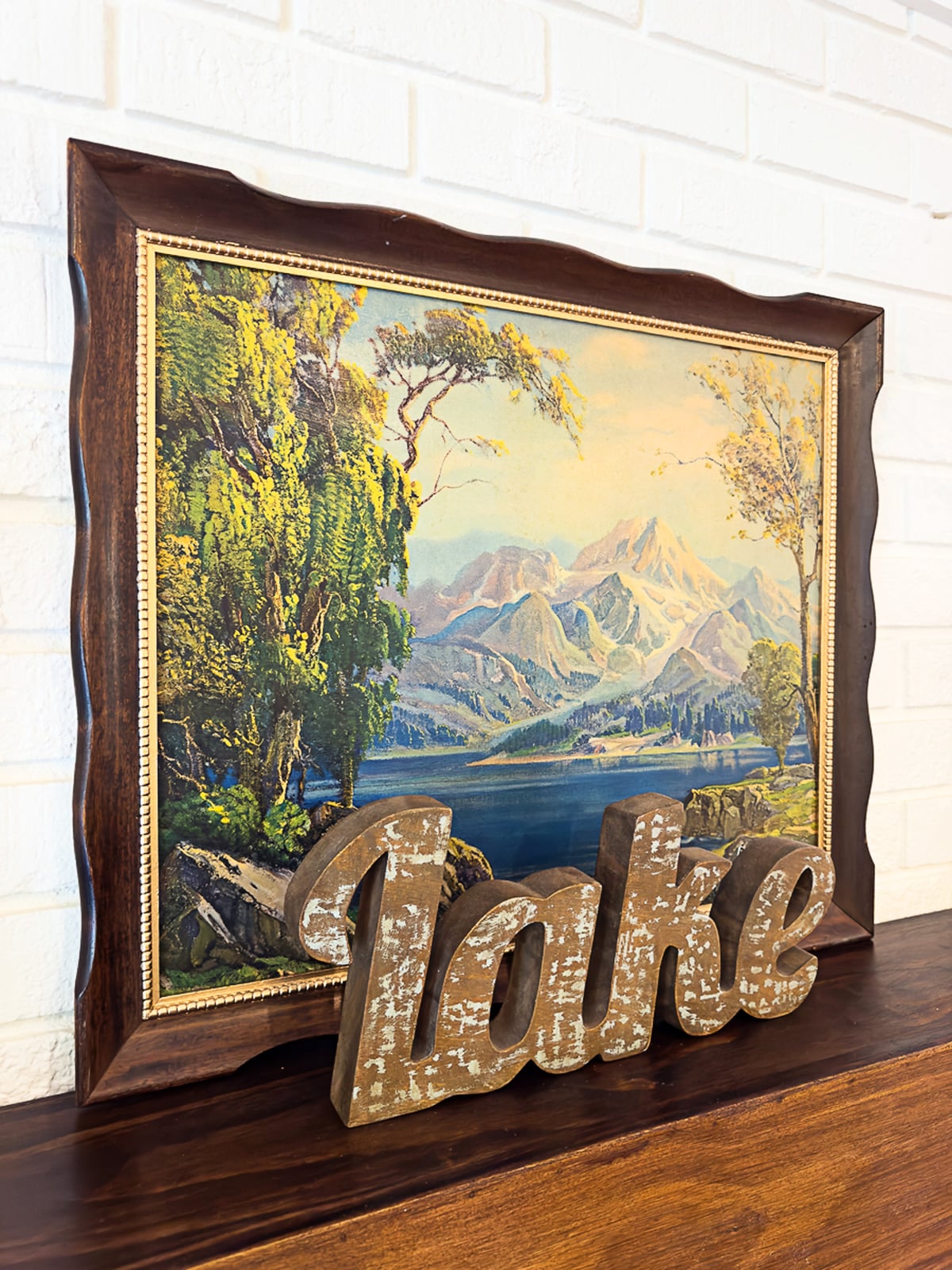A thrift store makeover using a piece of artwork and frame. This artwork is depicting a lake with trees along the edges.