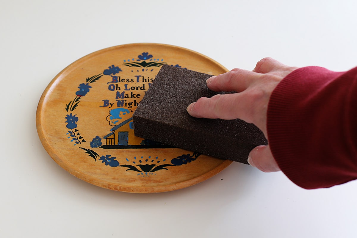 Sanding a wooden tray with a sanding block.