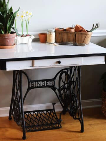 This eco-friendly upcycling project combines a thrifted porcelain enamel table with a vintage Singer sewing machine base for a unique retro-style table.