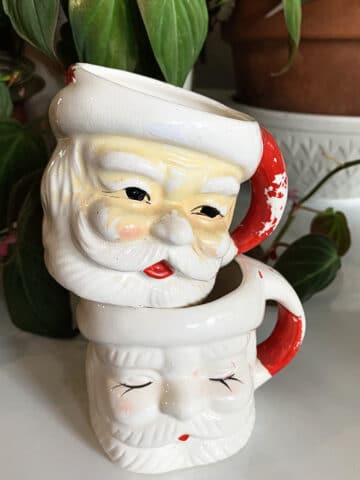 Two vintage Santa mugs stacked on top of each other which will be used in a piece of assemblage art using Dollar General holiday decorations.