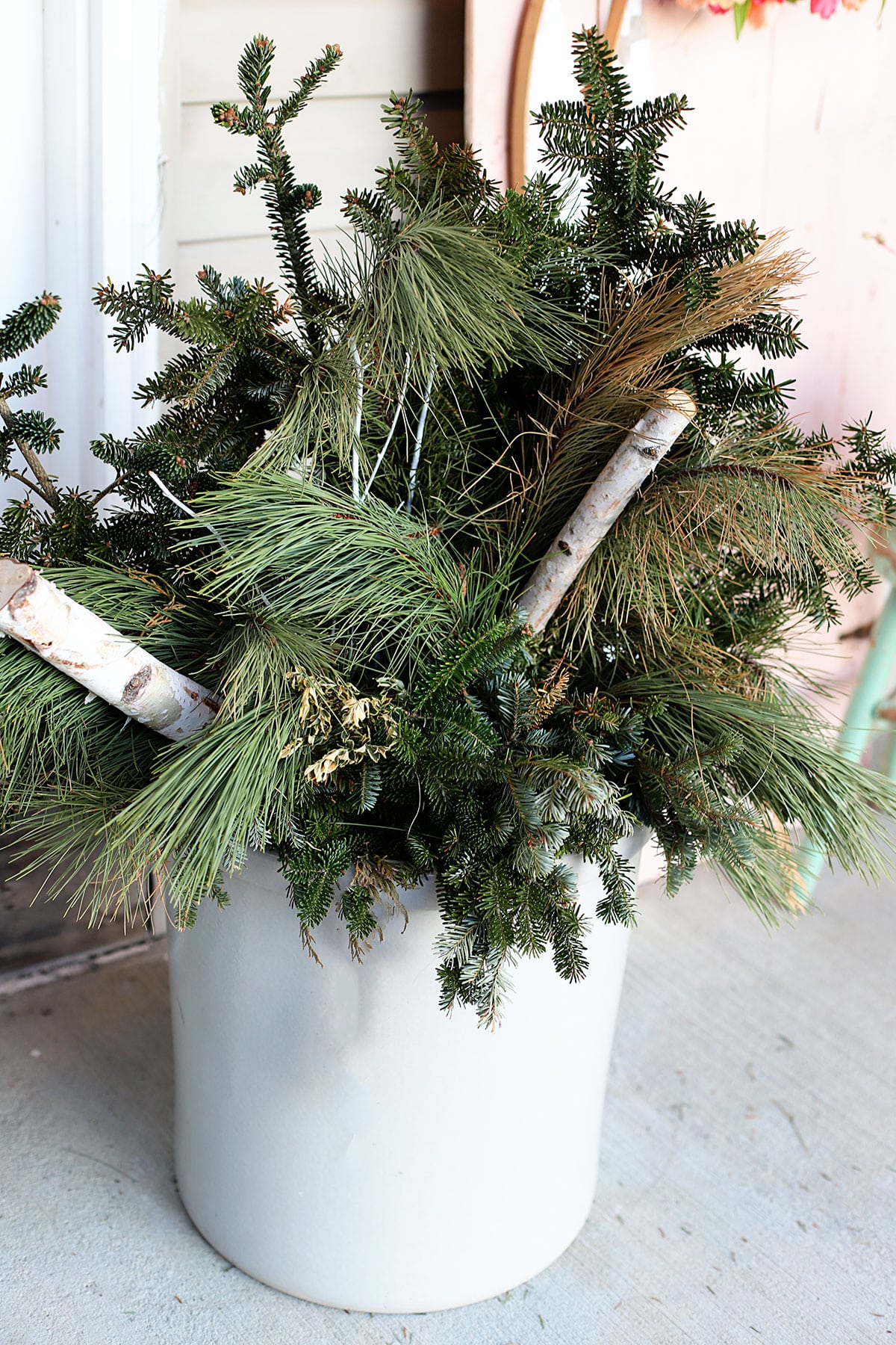 Leftover greenery in a large stoneware crock on the porch.