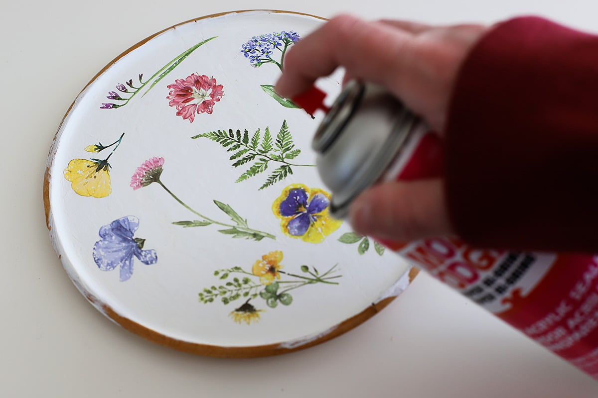 Spraying a water-based acrylic sealer to a wooden tray.